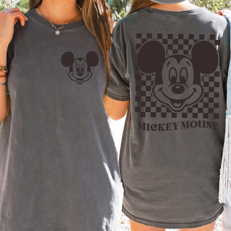 May include: Gray t-shirt featuring a Mickey Mouse graphic on the front and back. The front has a small Mickey Mouse face, while the back showcases a larger design with a checkered background and the text "MICKEY MOUSE".