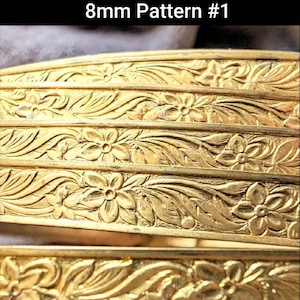 May include: Close-up of four gold-colored metal bangles with an intricate floral pattern. The bangles are 8mm wide and have a repeating design of leaves and flowers. The text "8mm Pattern #1" is visible at the top of the image.