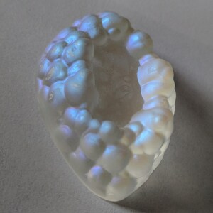 May include: A white agate geode with a hollow center and a iridescent, bubbly surface.