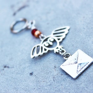 Peut inclure: Porte-cl&eacute;s hibou argent&eacute; avec des perles rouges et dor&eacute;es et un charme enveloppe argent&eacute;.