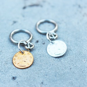 Peut inclure: Deux porte-cl&eacute;s argent&eacute;s avec des breloques rondes en m&eacute;tal. Un charme est en or et pr&eacute;sente un profil de femme. L'autre charme est en argent et pr&eacute;sente un motif.