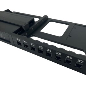 Può includere: Supporto per rack di rete nero con più porte etichettate da X0 a X7. Il rack ha una forma rettangolare con una sezione per alloggiare componenti elettronici. Il design include una serie di aperture rettangolari.