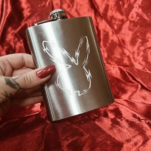 A stainless steel flask with a hand engraved playboy bunny made of razor wire.