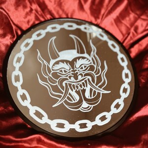 Hand engraved circle shaped wall hanging decor mirror in an American traditional tattoo style of a devil face framed in chain