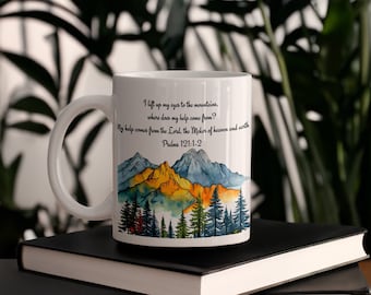 May include: White ceramic mug with a watercolor illustration of mountains and trees. The mug has a black handle and the text "I lift up my eyes to the mountains, where does my help come from? My help comes from the Lord the Maker of heaven and earth Psalms 121:1-2" printed on the side.