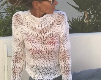 May include: A white crochet sweater with a loose fit and long sleeves. The sweater is made of a lightweight, airy fabric and has a delicate, open-weave design.
