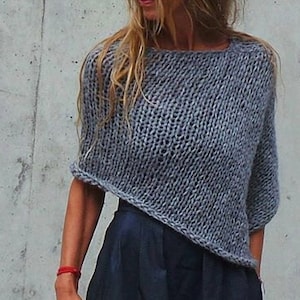 May include: A grey knitted sweater with a loose, oversized fit and a slightly asymmetrical hem.