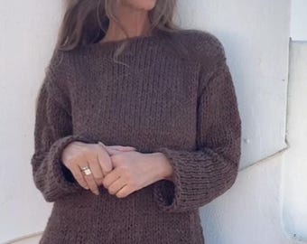 May include: A brown knitted sweater with long sleeves and a relaxed fit. The sweater is paired with brown corduroy shorts.