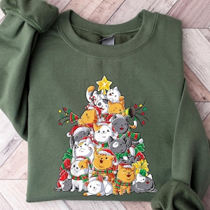 May include: A green sweatshirt with a Christmas tree design featuring a stack of cartoon cats wearing Santa hats and ornaments.