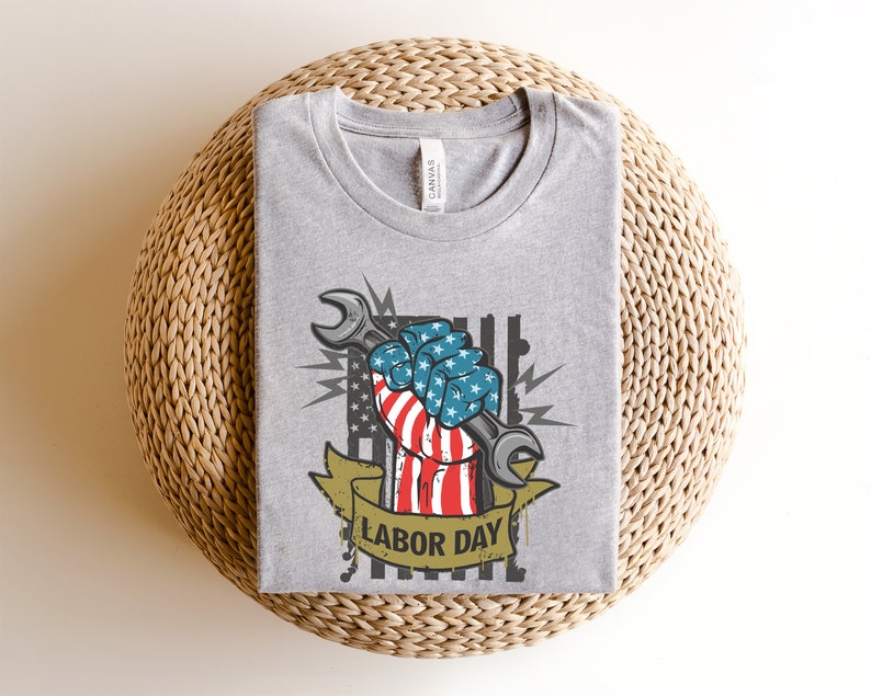 May include: Gray t-shirt with a graphic of a fist holding a wrench. The fist is wrapped in an American flag and the text "Labor Day" is below the graphic.