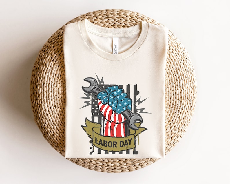 May include: A white t-shirt with a graphic of a fist holding a wrench. The fist is painted with the American flag colors and the text "Labor Day" is below the graphic.