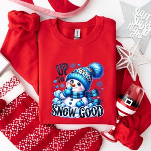 Peut inclure: Sweat-shirt rouge de No&euml;l avec un motif de bonhomme de neige et le texte "Up to Snow Good".