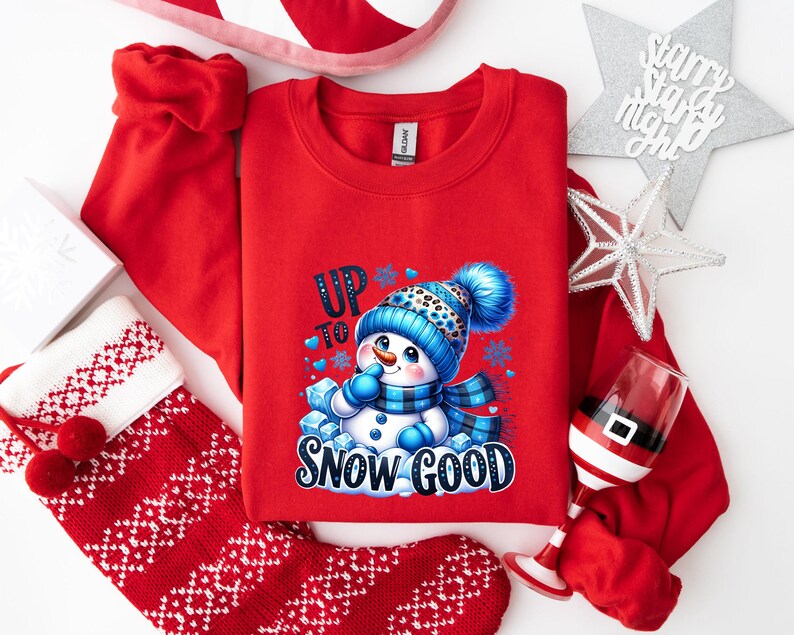 Peut inclure: Sweat-shirt rouge de No&euml;l avec un motif de bonhomme de neige et le texte "Up to Snow Good".