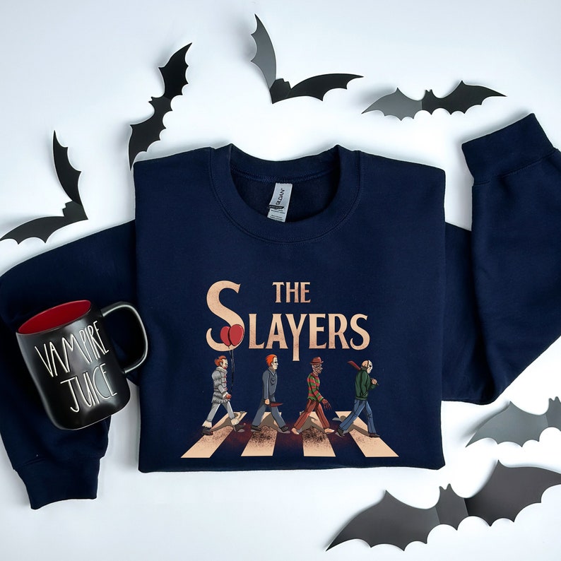 May include: A navy blue sweatshirt with a graphic of horror movie characters walking across a crosswalk. The graphic says "The Slayers" with a red balloon above the "S".