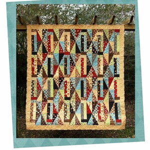 Könnte beinhalten: Ein farbenfroher Quilt mit einem geometrischen Muster aus Dreiecken und Rechtecken in Braun-, Blau-, Grün-, Rot- und Gelbtönen. Der Quilt hängt an einem Holzspalier vor einem Hintergrund aus grünem Laub. Der Quilt trägt den Titel "Sunday Brunch".