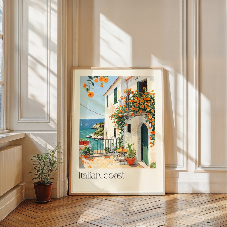 May include: A framed print of a painting depicting a white building with a balcony covered in orange flowers. The building is located on a cliff overlooking a blue body of water. The text "Italian Coast" is printed at the bottom of the print.