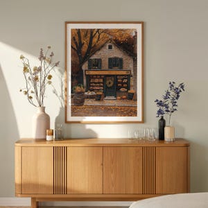 May include: A framed print of a quaint bakery storefront with a green door and windows, surrounded by autumn leaves. The bakery is decorated with a wreath and has a sign that reads "Le Boulanger".