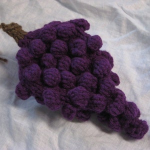 May include: A purple crocheted grape bunch with a brown stem.