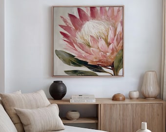 May include: A framed print of a pink protea flower with a white centre and green leaves. The artwork is in a light wood frame. The image is part of a home decor collection, suitable for living rooms or bedrooms.