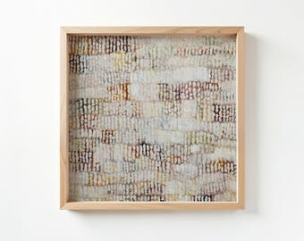 Könnte beinhalten: Abstraktes Kunstwerk in einem hellen Holzrahmen. Das Stück zeigt ein strukturiertes Muster in Weiß, Beige, Braun und Burgunderrot. Der Rahmen besteht aus hell getöntem Holz, das die neutrale Farbgebung des Kunstwerks unterstreicht. Quadratische Form.