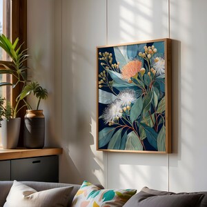 Puede incluir: Una impresi&oacute;n art&iacute;stica bot&aacute;nica enmarcada con un arreglo floral. La obra de arte presenta un fondo azul oscuro con hojas verdes, flores blancas y naranjas, y capullos amarillos. El marco de madera a&ntilde;ade un toque natural.