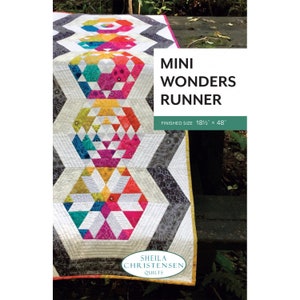 May include: A colorful quilted table runner with geometric patterns. The runner features a repeating design of hexagons filled with vibrant triangles in shades of pink, yellow, green, and orange. The text "MINI WONDERS RUNNER" is displayed, with a finished size of 18.5" x 48".