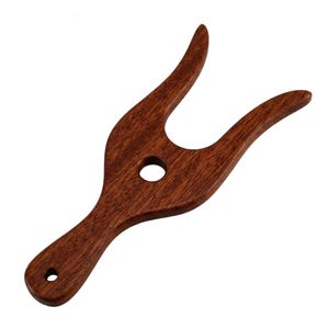 May include: A dark brown wooden boot jack with a smooth, polished finish. The tool features a Y-shaped opening at the top for removing footwear, a circular hole in the center, and a smaller hole at the base of the handle for hanging storage.