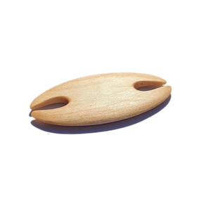 Könnte beinhalten: Ein hellfarbener Weinglashalter aus Holz. Der ovale Halter hat zwei gebogene Schlitze, um den Stiel eines Weinglases zu halten. Die Holzmaserung ist sichtbar. Der Halter ist so konzipiert, dass er auf dem Rand einer Weinflasche sitzt.