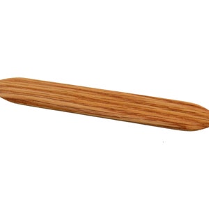 Könnte beinhalten: Ein Holzwerkzeug mit einer spitzen Spitze, das zum Glätten und Formen von Leder verwendet wird. Es hat eine natürliche Holzmaserung und eine hellbraune Farbe.