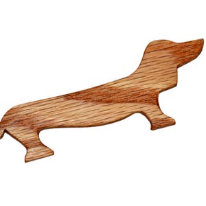 May include: A wooden dachshund-shaped ornament, carved from light brown wood with a natural wood grain finish.