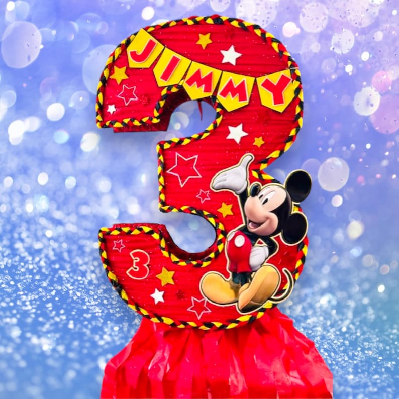 May include: Red and yellow Mickey Mouse themed pi&ntilde;ata shaped like the number 3. The pi&ntilde;ata has a banner that says "JIMMY" and features Mickey Mouse in the centre.