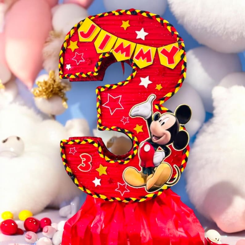 May include: Red and yellow Mickey Mouse themed pi&ntilde;ata shaped like the number 3. The pi&ntilde;ata has a red and yellow fringe at the bottom and says "JIMMY" on the top.