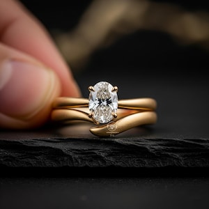 Brudringsset med matt finish, förlovningsring med 2,00 karat oval moissanit, vigselring med solitaire, justerbart armband i 14 karat guld med böjd öppen manschett