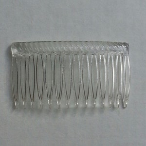 May include: A clear plastic hair comb with a twisted design. The comb has 12 teeth.