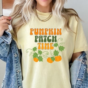 May include: A yellow t-shirt with the text "Pumpkin Patch Time" in a retro font. The text is surrounded by green vines with orange pumpkins.