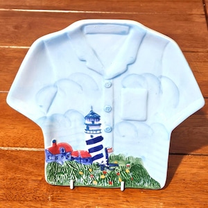 Pode incluir: Um conjunto de três canecas de cerâmica com uma cobertura salpicada de cor creme. Cada caneca apresenta um design pintado à mão diferente: uma folha azul e verde, uma flor amarela e uma baga vermelha. As canecas têm um design simples e moderno.