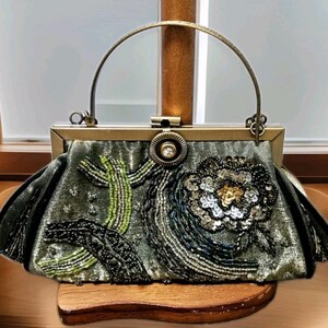 May include: An olive green handbag with a gold-toned frame and handle. The bag is decorated with beaded and sequined floral and abstract designs in green, black, and gold. The clasp has a central jewel.