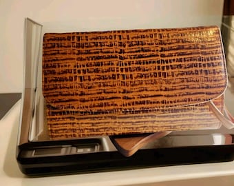 May include: A brown leather clutch purse with a crocodile-embossed pattern.