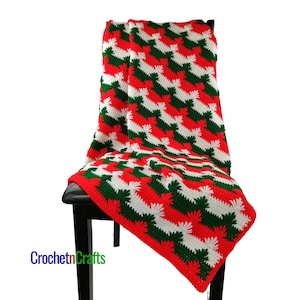 May include: A red, white, and green crocheted throw blanket with a zig-zag pattern. The blanket is draped over a black chair.