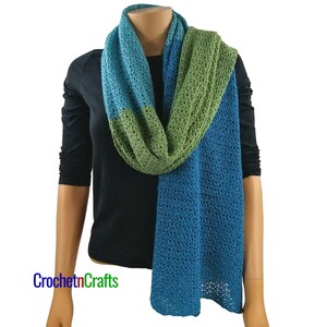 May include: A crocheted scarf with a blue, green, and teal color gradient. The scarf is made with a lacy stitch pattern.