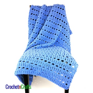 May include: A blue crocheted throw blanket draped over a chair. The blanket is made with a large stitch pattern and has a soft, fuzzy texture.