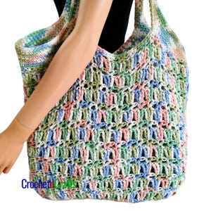 May include: A large crocheted tote bag with a colorful, multi-colored design in shades of green, blue, pink, and white.