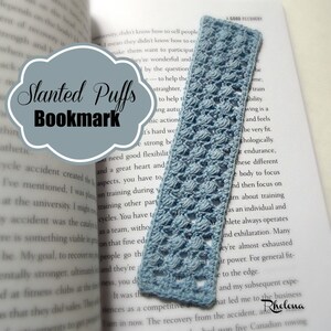 May include: A light blue crocheted bookmark with a slanted puff stitch pattern. The bookmark is laying on top of an open book with the text "Slanted Puffs Bookmark" visible.