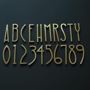 K&ouml;nnte beinhalten: Goldfarbene Metallbuchstaben und -zahlen, einschlie&szlig;lich A bis Y und 0 bis 9, sind auf einer dunkelgrauen Oberfl&auml;che angeordnet. Die Buchstaben und Zahlen haben eine elegante, moderne Schriftart.