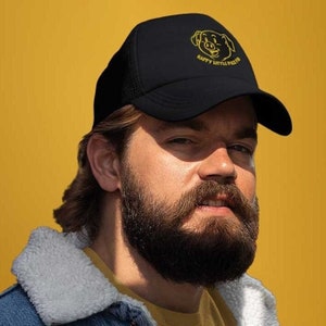 Puede incluir: Una gorra de camionero negra con un cerdo bordado en amarillo y el texto "Happy Little Piglet".