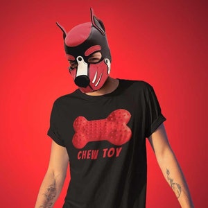 May include: A person wearing a black t-shirt with a red chew toy graphic and the text "CHEW TOY". The person is also wearing a black and red dog mask.