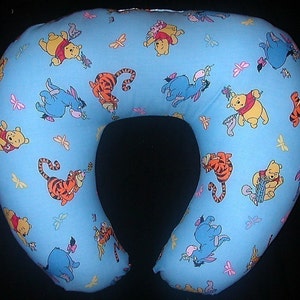 Puede incluir: Una almohada de embarazo en forma de U de color azul claro con un estampado de Winnie the Pooh y sus amigos. La almohada presenta imágenes de Winnie the Pooh, Tigger, Piglet y Eeyore.