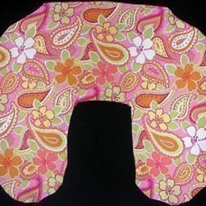Puede incluir: Una almohada de embarazo en forma de U, con un estampado de paisley y flores en rosa, verde y naranja. La almohada está diseñada para sostener el cuerpo durante el embarazo.