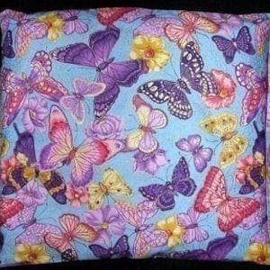 Può includere: Un cuscino in tessuto blu con un motivo di farfalle colorate. Le farfalle sono in tonalità di viola, rosa, giallo e bianco. Il cuscino è riempito con un materiale morbido e confortevole.