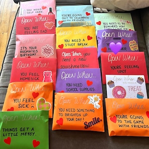 May include: A collection of colorful envelopes with handwritten messages on them. Each envelope has a different occasion or feeling written on it, such as "Open When You Need Self Care" or "Open When You Feel Homesick".